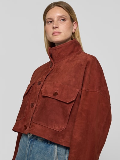 Frauenmodel trägt Jacke in Leder-Optik mit Pattentaschen Modell 'ARKLOW' von DRYKORN aus Baumwoll-Mix, Relaxed-Fit, Stehkragen, Knopfleiste, braune Farbe, samtige Textur, Ganzkörperansicht von vorne.