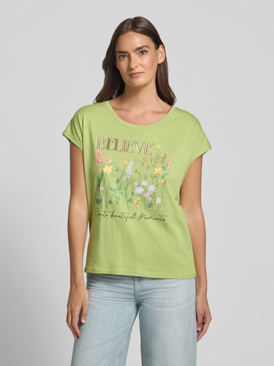Frauenmodel trägt T-Shirt mit Motiv-Print und Rundhalsausschnitt von Christian Berg Woman in Hellgrün aus Baumwoll-Viskose-Mix, Regular-Fit, florale Farben, Rückenlänge bei Größe S 56 cm, Ganzkörperansicht von vorne.