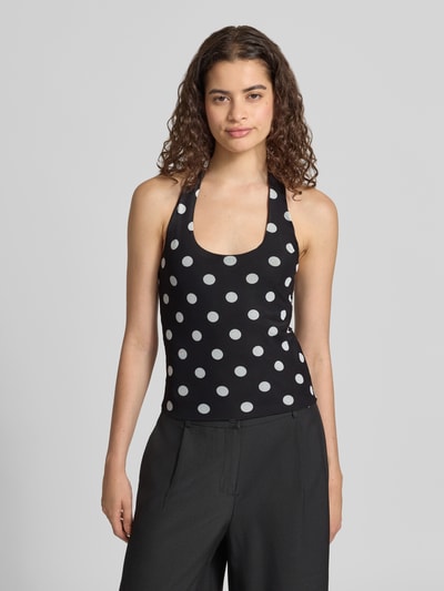 Frauenmodel trägt Neckholder-Top im Allover-Look Modell 'DOTTIE' von NOISY MAY® in Schwarz mit weißen Punkten, Material-Mix Slim Fit, Ganzkörperansicht von vorne.