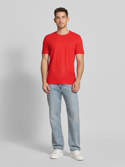 Männermodel trägt T-Shirt aus Baumwolle mit Rundhalsausschnitt von Christian Berg Men in Rot, Regular-Fit, Label-Detail, Ganzkörperansicht von vorne.