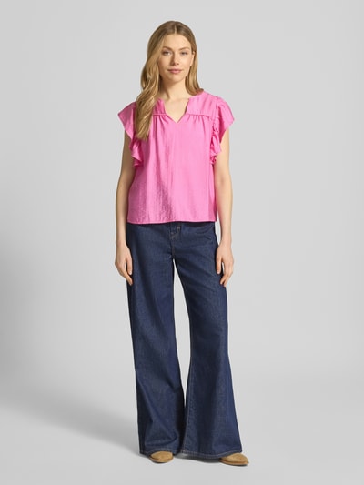 Frauenmodel trägt Bluse aus Viskose-Mix mit Rüschen Modell 'HETTA' von ICHI in Pink, Gerader-Schnitt, Serafino-Ausschnitt, Ganzkörperansicht von vorne.