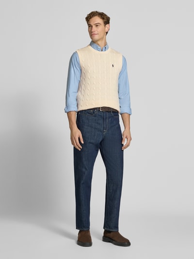 Männermodel trägt Regular Fit Pullunder aus reiner Baumwolle von Polo Ralph Lauren in Beige mit Zopfmuster, Ganzkörperansicht von vorne.