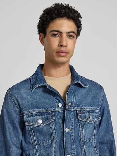 Męski model prezentuje Regular Fit Jeansjacke aus reiner Baumwolle Modell 'RYAN' von Tommy Jeans, tkanina stylizowana na denim, splot twill, naszywka z logo, wytłaczane logo, długi rękaw, wpuszczane kieszenie, brustasza, wykładany kołnierz, listwa guzikowa, widok na górną część przodu, zbliżenie na klatkę piersiową.