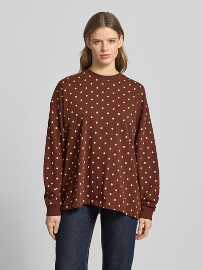 Kobieta nosi Sweatshirt mit überschnittenen Schultern von OH APRIL, luźny krój, okrągły dekolt, brązowy w żółte kropki, długość tyłu w rozmiarze S: 69 cm, zakończenia rękawów elastyczne, całkowity widok z przodu