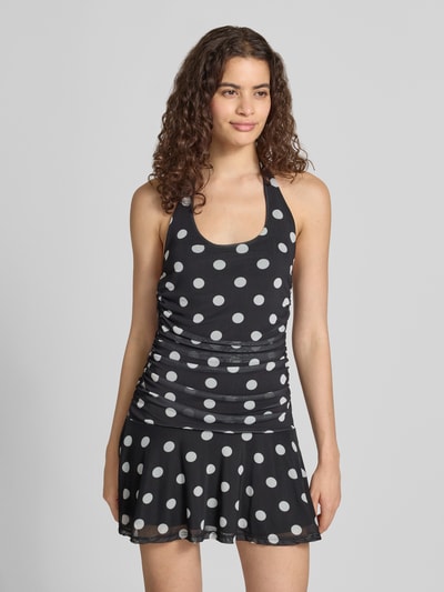 Frauenmodel trägt Neckholder-Minikleid im Allover-Look Modell 'DOTTIE' von NOISY MAY®, schwarzer Stoff mit weißen Punkten, Slim Fit, Material-Mix mit Stretch-Anteil, Ganzkörperansicht von vorne.
