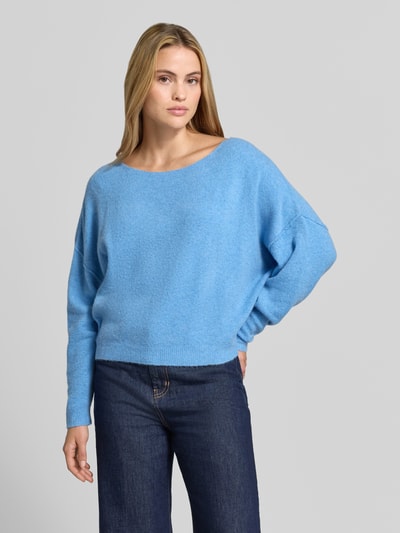 Frauenmodel trägt Relaxed Fit Strickpullover aus Material-Mix mit Leinen-Anteil von American Vintage in Hellblau mit gerippten Abschlüssen, überschnittenen Schultern, Langarm und Rundhalsausschnitt, kombiniert zu dunkler Jeans; Damen Strickpullover Modernes Design, Ganzkörperansicht von vorne.