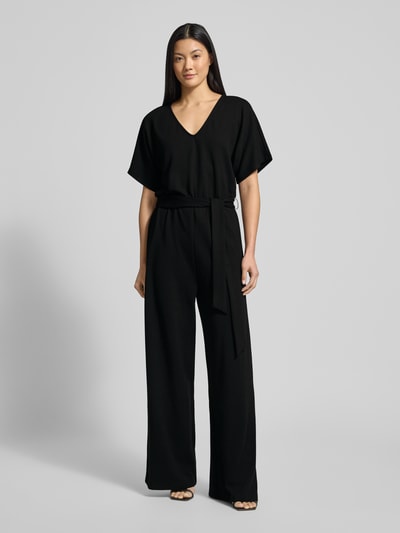 Frauenmodel trägt schwarzen Jumpsuit mit Bindegürtel Modell 'Renata' von GUIDO MARIA KRETSCHMER WOMAN, Viskose-Mix, Ganzkörperansicht von vorne.