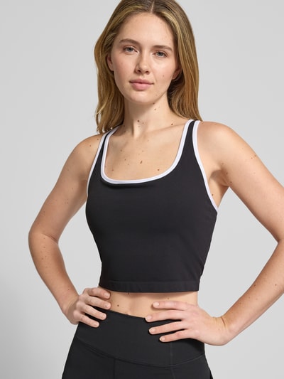 Frauenmodel trägt Cropped Top mit integriertem Bustier von Fabletics aus elastischem Material-Mix, Schwarz mit Weiß, Nahaufnahme Oberkörper.