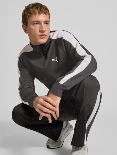 Männermodel trägt Sweatjacke mit Label-Print von PUMA PERFORMANCE in Schwarz mit weißen Streifen, Material-Mix, Regular-Fit, Ganzkörperansicht von vorne.