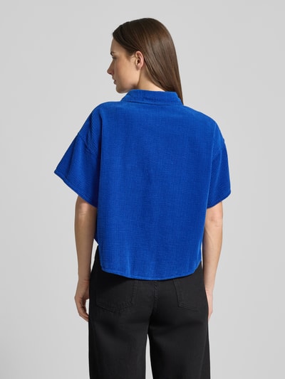 Modelka nosi Cropped Hemdbluse mit Knopfleiste Modell 'PADOW' od American Vintage, czysta bawełna, luźny krój, kolor niebieski, widok całej sylwetki z tyłu.