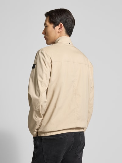 Männermodel trägt Jacke mit Stehkragen Modell 'Calvin' von Brax in Beige, glatte Baumwoll-Mix-Textur, Rückansicht, Ganzkörperansicht.