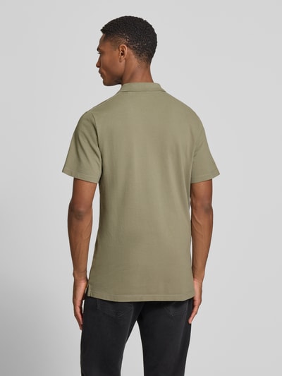Männermodel trägt Regular Fit Poloshirt aus reiner Baumwolle von s.Oliver RED LABEL in Olive, Piqué-Struktur, Ganzkörperansicht Rückansicht.