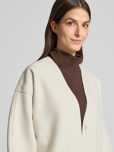 Vrouwenmodel draagt Relaxed Fit Strickjacke mit Viskose-Anteil Modell 'Juice' van Vila, beige tinten, zachte textuur, detailopname bovenlichaam, materiaal-mix, oversized schouders, dames cardigan.