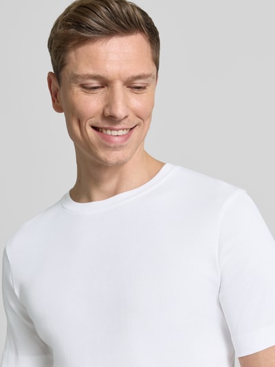 Männermodel trägt weißes Herren T-Shirt mit Rundhalsausschnitt Modell 'ENIL' von Drykorn, Reine Baumwolle, Slim Fit, Nahaufnahme Oberkörper.