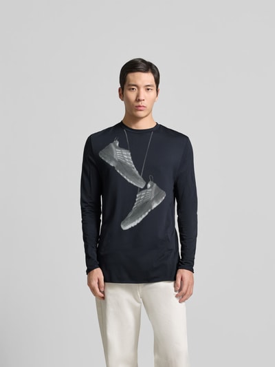 Männermodel trägt Regular Fit Longsleeve mit Motiv-Print von MM6 Maison Margiela, schwarzer Stoff, Strukturmuster, Ganzkörperansicht von vorne.