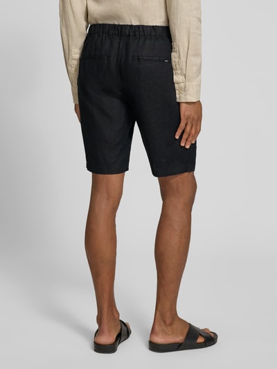 Męski model nosi Leinen Shorts mit Eingrifftaschen Modell 'PANDRUP' od Casual Friday z czystego lnu, krój straight fit, kolor czarny, widok całej sylwetki z tyłu