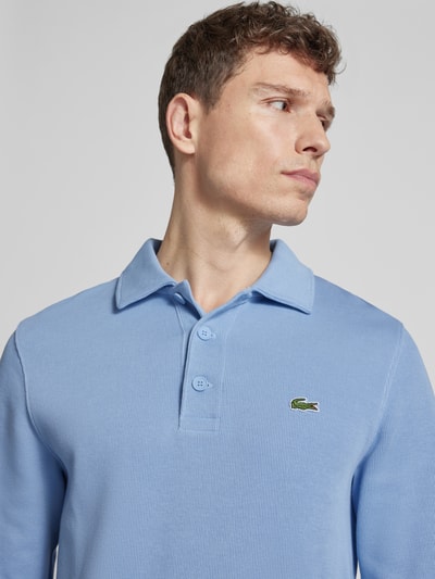 Männermodel trägt Regular Fit Sweatshirt aus reiner Baumwolle von Lacoste in Hellblau, unifarben, Polokragen, Logo-Stitching, Nahaufnahme Oberkörper.