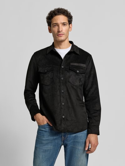Männermodel trägt Oversized Hemdjacke mit Logo-Stitching Modell 'Ekel' von HUGO in Schwarz, weiche Struktur, Jeans, Herren Hemdjacke, Ganzkörperansicht von vorne.