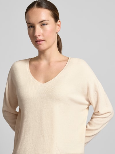 Frauenmodel trägt Strickpullover aus Viskose-Mix Modell 'FREYJA' von Oui, cremefarben, feine Rippenstruktur, Nahaufnahme Oberkörper. Damen Strickpullover, Gerade Passform, V-Ausschnitt, Überschnittene Schultern, Rückenlänge 59 cm, Ärmellänge 63 cm.