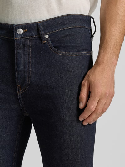 Männermodel trägt Slim Fit Jeans aus Baumwoll-Mix Modell 'Delaware' von BOSS in dunklem Blau, glatte Textur, Nahaufnahme Oberschenkel. Herren Slim Fit Jeans von BOSS.