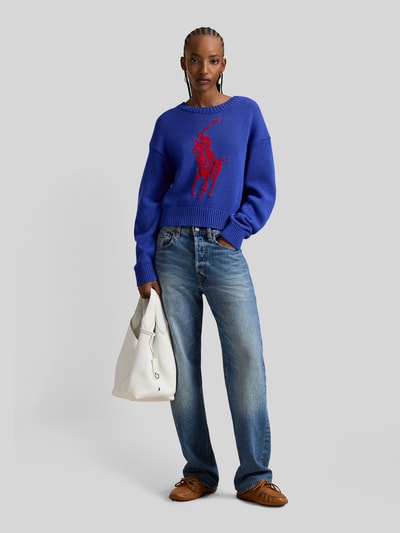 Frauenmodel trägt Regular Fit Strickpullover aus reiner Baumwolle von Polo Ralph Lauren in Two Tone Optik mit großem Pony-Intarsia, Crew Neck, Rippenbündchen, Stricktextur, Ganzkörperansicht von vorne.