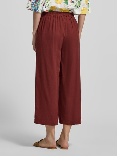 Frauenmodel trägt Regular Fit Culotte aus Viskose-Leinen-Mix Modell 'MYMILO' von Vero Moda, efekt: jednolity kolor, ceglasta czerwień, krój regular fit, częściowy ściągacz, wpuszczane kieszenie, wykończenie materiału: cieniowana przędza, mieszanka wiskozy i lnu, Ganzkörperansicht Rückansicht.