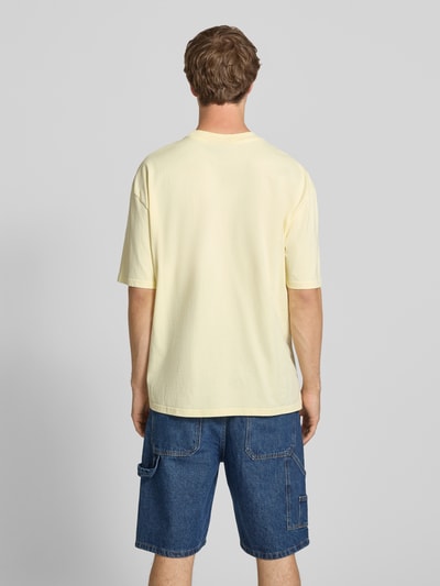 Männermodel trägt Oversized T-Shirt mit Label-Stitching von Pegador in Creme, Baumwoll-Mix, Rundhalsausschnitt, Rückenlänge 70 cm, Ganzkörperansicht Rückansicht.