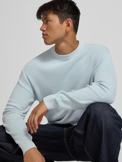 Männermodel trägt Regular Fit Strickpullover aus reiner Baumwolle von REVIEW in Hellblau, Rundhalsausschnitt, Nahaufnahme Oberkörper.
