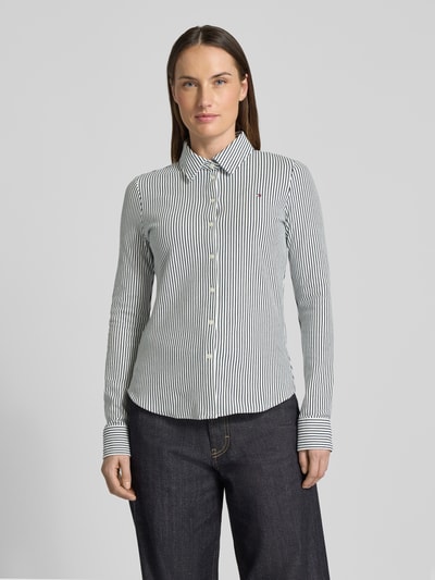 Vrouwenmodel draagt Slim Fit Hemdbluse aus Baumwoll-Mix van Tommy Hilfiger met all-over streeppatroon, logostiksel, lange mouw, knoopsluiting, katoenmengsel, slim fit, hemdkraag, manchet; volledige voorkantopname.