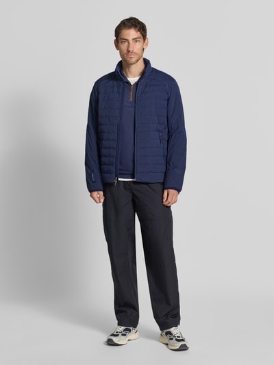 Męski model nosi Regular Fit Sweatjacke mit Steppung von Polo Ralph Lauren, granatowy kolor, widoczna tekstura pikowania, Ganzkörperansicht von vorne.