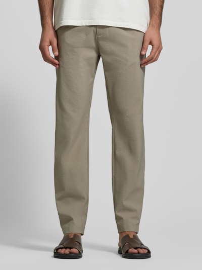 Męski model trägt Slim Fit Stoffhose mit Strukturmuster von CRUNA, elastyczna mieszanka materiałów, krój slim fit, kieszenie, fakturowany wzór, szerokość w rozmiarze 50: 44 cm, długość wewnętrzna nogawki 79 cm, wpuszczane kieszenie, elastyczny pas, kolor beżowy, widok całej sylwetki z przodu.