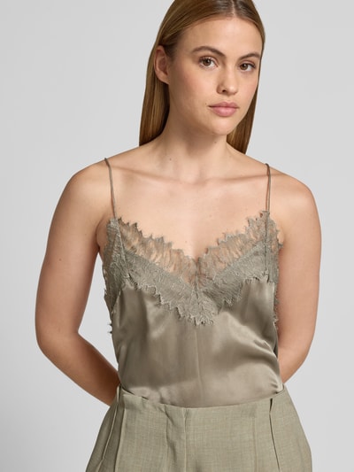 Frauenmodel trägt Bluse aus Satin mit Spitzenbesatz von Iro in Beige mit V-Ausschnitt und Spaghettiträgern, Nahaufnahme Oberkörper.
