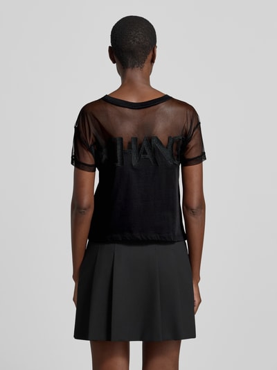 Frauenmodel trägt Regular Fit T-Shirt mit Logo-Stitching von ARMANI EXCHANGE aus schwarzer, semitransparenter Baumwolle, Ganzkörperansicht Rückansicht.