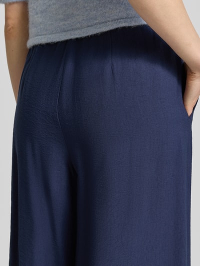Männermodel trägt granatową Wide Fit Stoffhose aus Viskose-Mix Modell 'Frencis' von STEHMANN, z elastycznym pasem i kieszeniami, Szerokość w rozmiarze 36: 38 cm, długość nogawki wewnętrznej 77 cm, tekstura gładka, zbliżenie na tył.