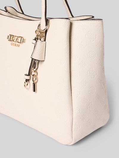 Produktfoto, cremefarbene Handtasche mit Anhänger und Label-Applikation von Guess, strukturierte Oberfläche, sichtbarer Reißverschluss, Tragehenkel, Hauptfach, Maße: 39x28x13 cm, Länge Schulterriemen 63 cm