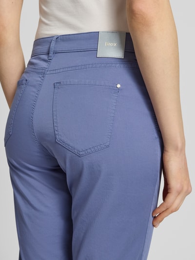 Kobieta nosi spodnie z wpuszczanymi kieszeniami Hose mit Eingrifftaschen Modell 'Carola' od Brax, mieszanka bawełny i lyocellu, krój regular fit, szerokość w rozmiarze 36K: 39 cm, długość wewnętrzna nogawki w rozmiarze 36K: 76 cm, detaliczna faktura, jednolity kolor, ujęcie z tyłu zbliżenie na kieszeń