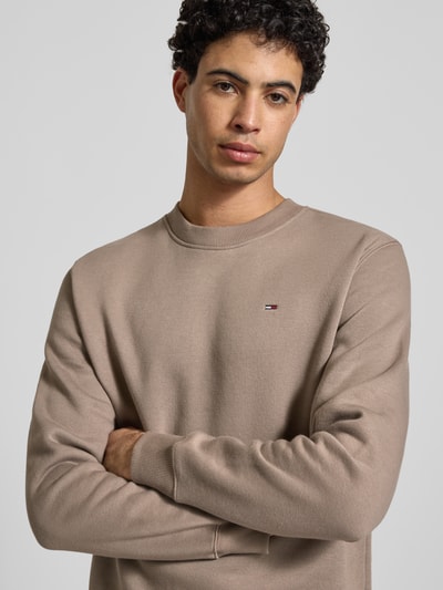 Męski model nosi Regular Fit Sweatshirt aus Baumwoll-Mix od Tommy Jeans, efekt: jednolity kolor, wyhaftowane logo, mieszanka bawełny, dzianina dresowa, okrągły dekolt, długi rękaw, prążkowane zakończenia, zdjęcie: zbliżenie na górną część ciała z przodu