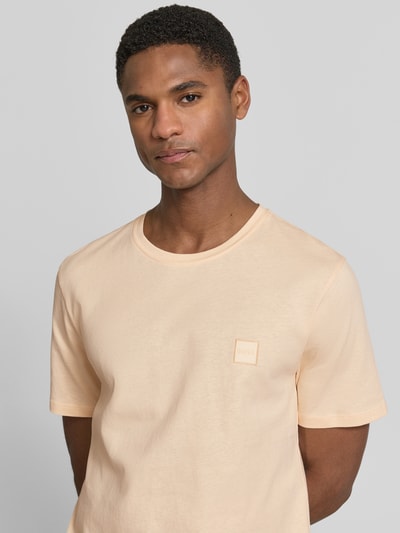 Męski model nosi Regular Fit T-Shirt aus reiner Baumwolle Modell 'TALES' von BOSS Orange, efekt: jednolity kolor, naszywka z logo, okrągły dekolt, krótki rękaw, czysta bawełna, zbliżenie na górną część ciała.