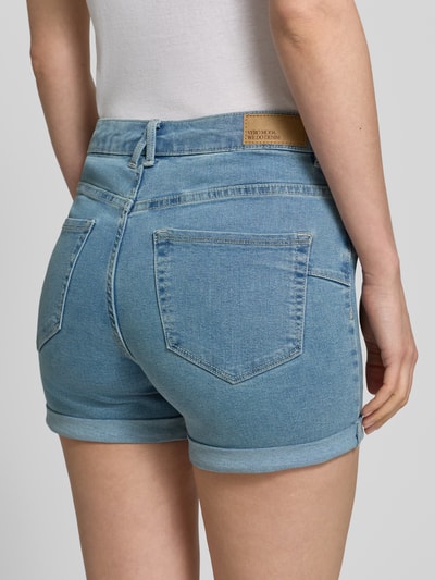 Vrouwenmodel draagt Regular Fit Jeansshorts uit katoenmix model 'LUNA' van Vero Moda in denimlook met labelpatch, detailopname rugaanzicht.