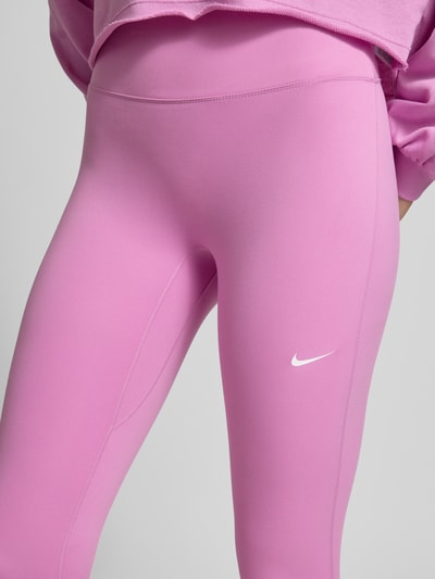Frauenmodel trägt Leggings mit Logo-Print Modell 'One' von NIKE TRAINING in Pink, Material-Mix mit Stretch-Anteil, Nahaufnahme Oberkörper.