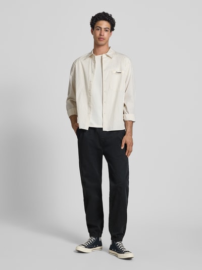 Männermodel trägt Straight Fit Jeans aus reiner Baumwolle von Tommy Jeans, schwarze Denim-Optik, 5-Pocket-Design, Ganzkörperansicht von vorne.