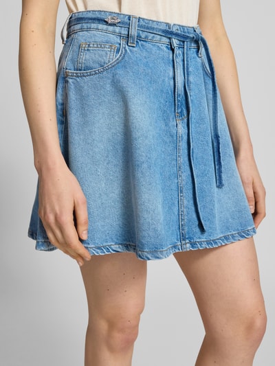 Frauenmodel trägt Jeansrock aus Baumwolle mit Bindegürtel von Liu Jo White, A-Linie, Minirock, hellblau, Nahaufnahme Oberkörper.