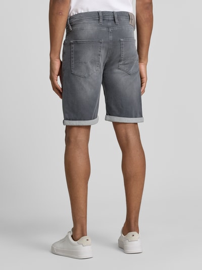 Männermodel trägt Bermudas in Denim-Optik von MAC in Grau mit Used-Look, Eingrifftaschen und Umschlag, Ganzkörperansicht Rückansicht.