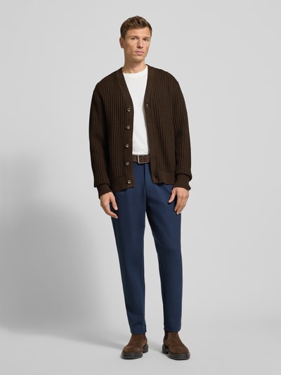 Männermodel trägt Regular Fit Strickjacke aus reiner Baumwolle Modell 'TOM' von Selected Homme in Braun, Waffelstruktur, Optik: Unifarben, Grobstrick, Knopfleiste, Rundhals, Langarm, Ärmelabschluss und Rumpfabschluss gerippt, Ganzkörperansicht von vorne.