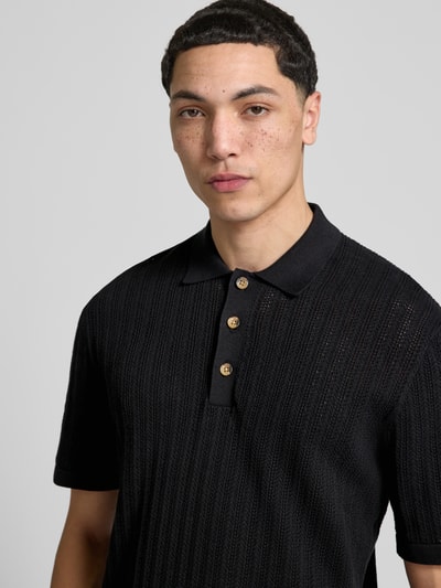 Männermodel trägt Regular Fit Poloshirt aus Baumwoll-Mix Modell 'MOON' von Only & Sons in schwarzer Strickoptik mit Struktur-Muster, Nahaufnahme Oberkörper.