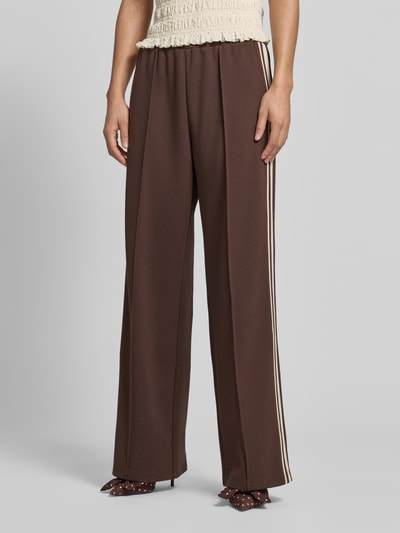Frauenmodel trägt Jog Pants mit französischen Eingrifftaschen von Jake*s Casual in Braun, Wide-Leg-Fit, Material-Mix mit Stretch-Anteil, Elastischer Bund, Detailaufnahme Vorderseite.