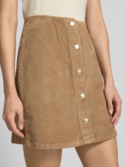 Kobieta nosi spódnicę mini z mieszanki bawełny w kolorze beżowym, regular fit Mini-Rock aus Baumwoll-Mix model 'ETTA' od Vero Moda, damska spódnica mini VERO MODA, zbliżenie na dolną połowę ciała.