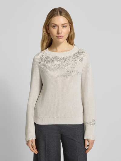 Kobiece modelka nosi Sweter z dzianiny z obszyciem ozdobnymi kamieniami od monari, mieszanka bawełny, krój regular fit, okrągły dekolt, długość tyłu 60 cm, długość rękawów 64 cm, jasny kolor, faktura gładka, widok całej sylwetki z przodu.