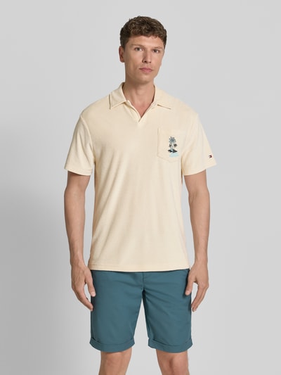 Männermodel trägt Regular Fit Poloshirt aus Frottee von Tommy Hilfiger, sandfarben, Polokragen, Brusttasche, Ganzkörperansicht von vorne.
