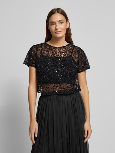 Frauenmodel trägt Cropped T-Shirt aus Mesh mit Pailletten von LACE & BEADS, półprzezroczysty materiał, okrągły dekolt, czarne cekiny, damski t-shirt, długość tyłu 41 cm dla rozmiaru S, Ganzkörperansicht von vorne.